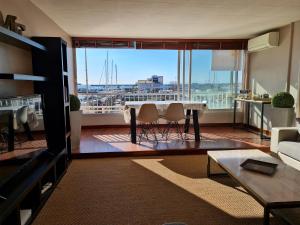 a living room with a table and a large window at Résidence de standing la Pêcherie Spacieux T3 comme un cocon familial vue mer et sur l'avant port Sur le bout du bout de Cap d'Agde seule cap en Occitanie in Cap d'Agde
