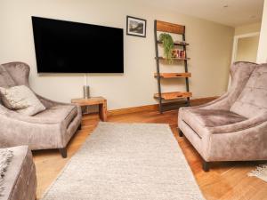 sala de estar con 2 sillas y TV de pantalla plana en 9 Riverside Walk, en Skipton