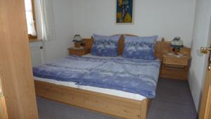 ein Bett mit blauer Bettwäsche und blauen Kissen in einem Schlafzimmer in der Unterkunft Fewo Ellen in Schönau am Königssee