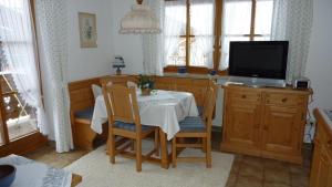 ein Esszimmer mit Tisch und Fernseher in der Unterkunft Fewo Ellen in Schönau am Königssee