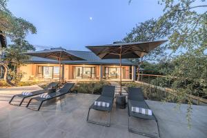 eine Gruppe von Stühlen und Sonnenschirmen auf einer Terrasse in der Unterkunft Little Kubu Lodge in Hoedspruit