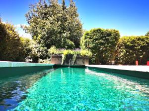 un bassin d'eau bleue avec des arbres en arrière-plan dans l'établissement Provence Km28, à Gordes