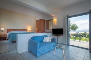 a hotel room with a bed and a blue couch at Palatia Village Hotel Apartments in Hersonissos