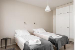 two beds in a white room with towels on them at Apartments Borg Antinkatu in Pori