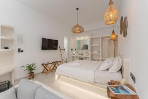 ein weißes Schlafzimmer mit einem Bett und ein Wohnzimmer in der Unterkunft Adama's Suites in Naxos Chora