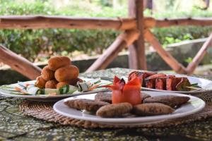 dois pratos de alimentos numa mesa com carne e produtos hortícolas em Chanya Lodge em Moshi