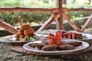 two plates of food on a table with meat and vegetables at Chanya Lodge in Moshi