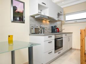 a kitchen with white cabinets and a glass counter top at Hus in de Sünn in Insel Poel