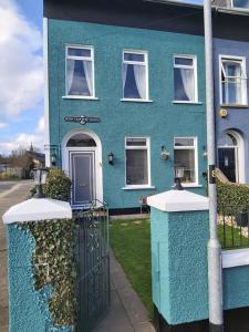 a blue house with a gate in front of it at The Tramway House in Carrickfergus