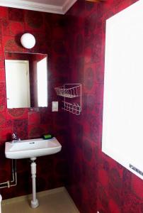 un bagno rosso con lavandino e specchio di Ekesberget Stugby stuga 10 a Ekshärad
