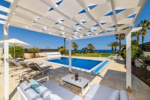 eine Terrasse mit einer weißen Pergola und einem Pool in der Unterkunft Royal Beachfront Villa in Protaras