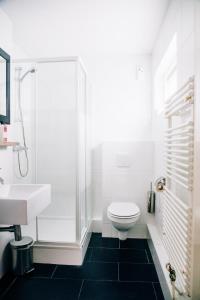 a white bathroom with a sink and a toilet at Fris. in Cadzand