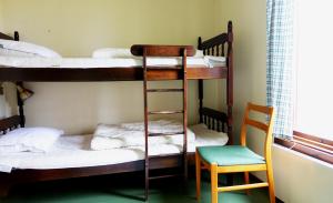 two bunk beds in a room with a chair and a ladder at Stuga Ekesberget Stugby in Ekshärad