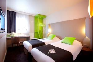 two beds in a hotel room with green accents at Campanile Lille Euralille in Lille