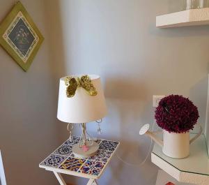 una mesa con una lámpara y un jarrón de flores en APARTAMENTO CORTADURA BEACH en Cádiz