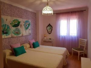 1 dormitorio con 2 camas y lámpara de araña en APARTAMENTO CORTADURA BEACH, en Cádiz