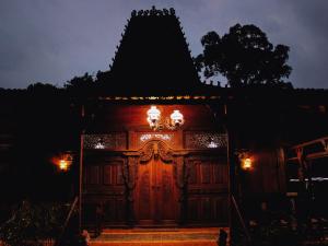 un edificio de madera con luces encendidas por la noche en Cokro Hinggil - Traditional View, en Sleman