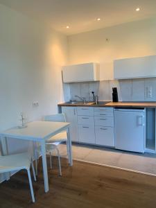 uma cozinha com armários brancos e uma mesa e cadeiras em FeWo an der Warnow unweit der Ostsee em Rostock
