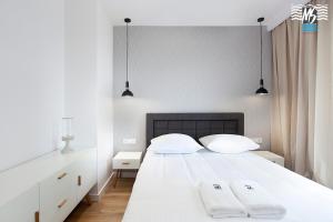 een slaapkamer met een wit bed en 2 handdoeken bij MS Apartments Sky Tower V in Gdańsk