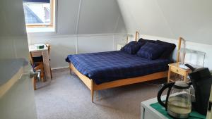 een slaapkamer met een bed met een blauw dekbed en een raam bij Logies bij Wandelpad te Holten in Holten