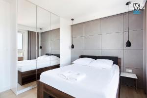 1 Schlafzimmer mit 2 Betten und einem Wandspiegel in der Unterkunft MS Apartments Sky Tower VIII in Danzig
