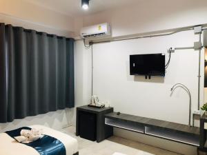 ein Hotelzimmer mit einem TV und einem Bett sowie einem Zimmer in der Unterkunft The Inka Hotel in Nakhon Si Thammarat