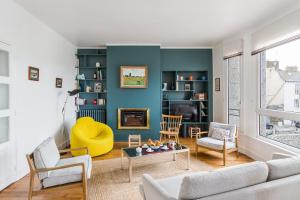 un salon avec un canapé et une chaise jaune dans l'établissement Le Hauturier - appartement de standing avec vue mer, à Saint-Malo