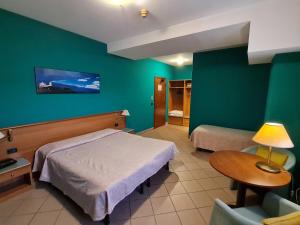 a hotel room with two beds and a table and a lamp at Modo Hotel in Vercelli