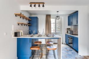 a kitchen with blue cabinets and bar stools at Le Cap Cézembre - Intra-Muros Saint-Malo in Saint Malo
