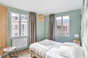 a bedroom with a bed and two windows at Le Cap Cézembre - Intra-Muros Saint-Malo in Saint Malo