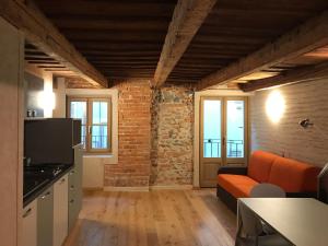 uma sala de estar com um sofá laranja e uma parede de tijolos em VIRASOL IN CITTÁ, bilocale ACQUA em Cuneo