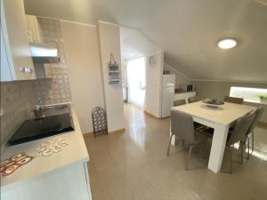 una cucina e una sala da pranzo con tavolo e sedie bianchi di Casa Flavia, Montesilvano Marina a Montesilvano