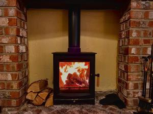 a stove with a fire in a brick fireplace at Hartendale in Flamborough