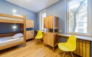 a bedroom with bunk beds and a desk and two yellow chairs at Friday Hostel in Odesa