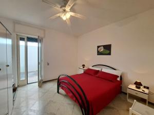 1 dormitorio con cama roja y ventilador de techo en Casa Vittorio a 100m dalla Sabbia, en Lido Marini