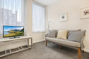 a living room with a couch and a tv on a table at Central City Studio Near Dining and Bars in Melbourne