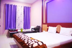 a bedroom with a bed and purple curtains at Hotel Shree Hari in Deoghar