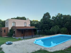 a villa with a swimming pool in front of a house at El Recreo, Villa Residencial Laguna La Brava in Villa Residencial Laguna Brava