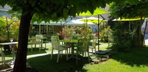 een tafel en stoelen in een tuin met parasols bij Hotel Le Lion d'Or in Saint-Geniez-dʼOlt