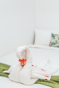 un animal de toallas blanca sosteniendo una flor en una cama en The Palms At Coco Beach en Coco