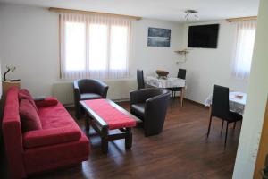 sala de estar con sofá rojo y sillas en Harri's BnB in Kandersteg, Ferienwohnung en Kandersteg