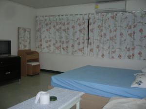 a bedroom with a bed and a tv and curtains at Poppular Palace Don Mueang Bangkok in Bangkok