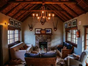 a living room with a fireplace and a chandelier at Camp Acacia - Private Safari Lodge with Pool near Amakhala in Paterson