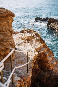un conjunto de escaleras en las rocas cerca del océano en Apartaments Cap Sa Sal, en Begur