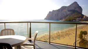 balkon ze stołem i krzesłami oraz plażą w obiekcie Apartamentos Hipocampos Unitursa w mieście Calpe