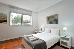 a white bedroom with a bed and a window at O´Porto Covelo Flat in Porto