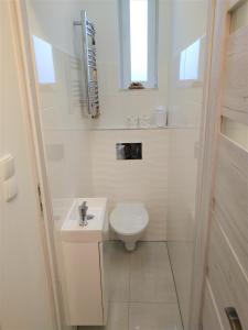 a white bathroom with a toilet and a sink at Apartament Sikorki in Nowy Sącz