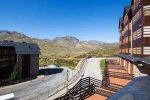 a road next to a building with mountains in the background at Lanuza by PIRINEOS 360 - Garaje y trastero in Formigal