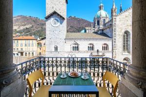 a table with a plate of food on a balcony with a clock tower at Dome's Charme - The House Of Travelers in Como