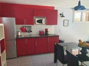 Villa Silhouette Cap d'Ail في كاب دايل: مطبخ مع دواليب حمراء وطاولة